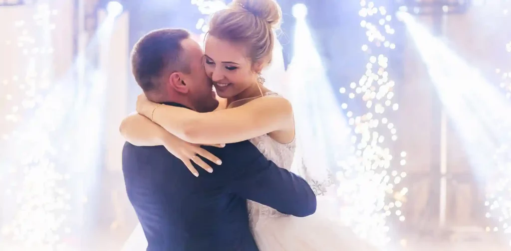 Bride and groom sharing their first dance in front of their wedding dj -  romantic lighting, with a magical atmosphere.