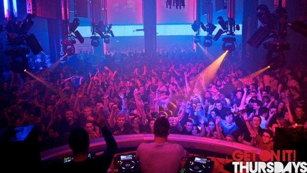 DJ Ashley Tapster and fellow DJ performing to a full dancefloor with vibrant lighting.