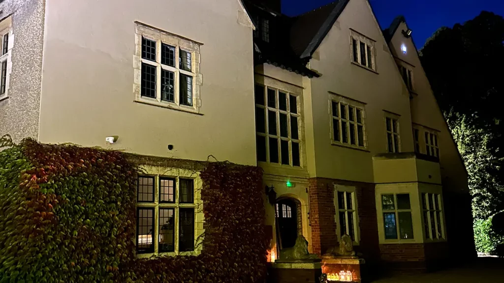 Plum Park Manor wedding venue exterior at night with ivy-covered walls and glowing lanterns.