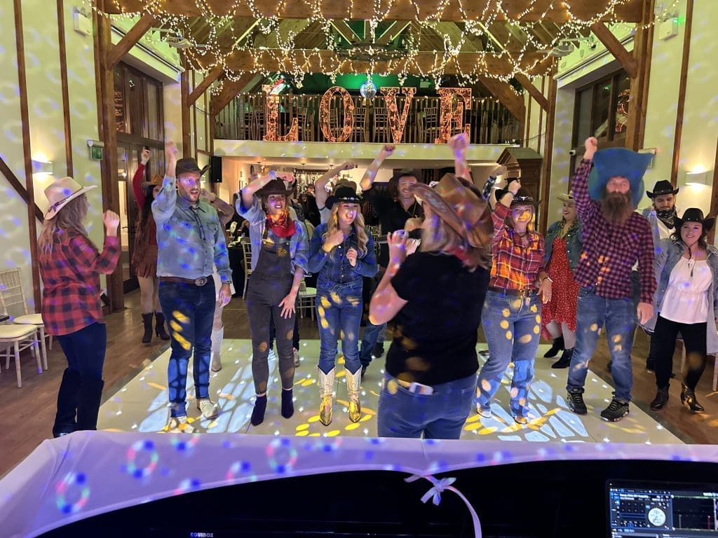 Guests dressed in themed outfits dancing under fairy lights at Winter’s Tale Country Barn in Buckinghamshire.
